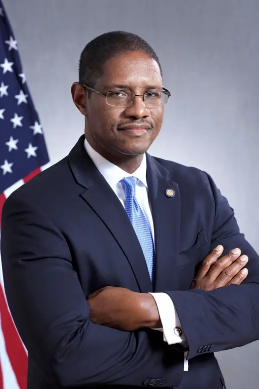 Commissioner William Clyburn, Jr., in a dark suit, standing before a United States flag.